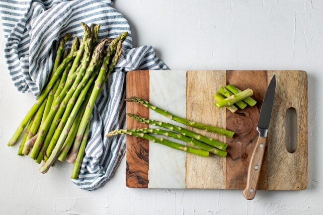 cutting asparagus on cutting board with knife