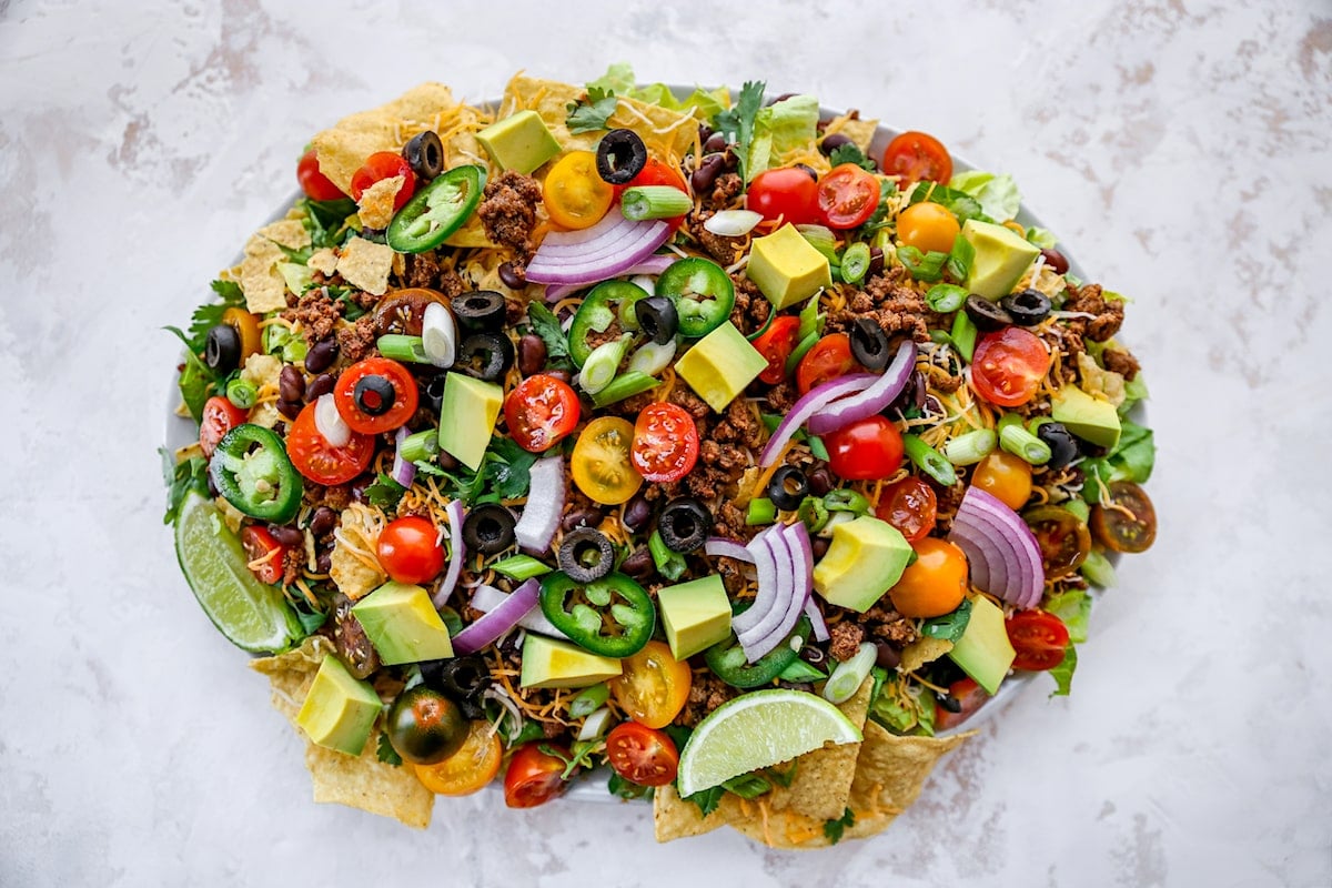 taco salad on platter with taco meat and toppings. 