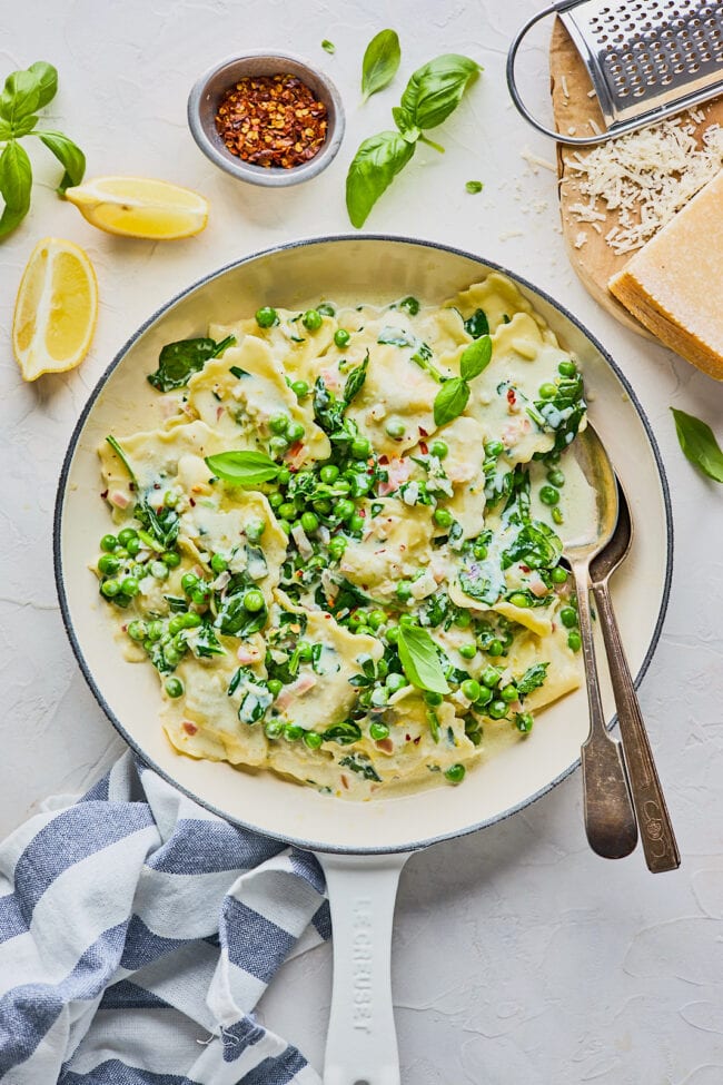 creamy lemon ravioli with spinach and peas in skillet