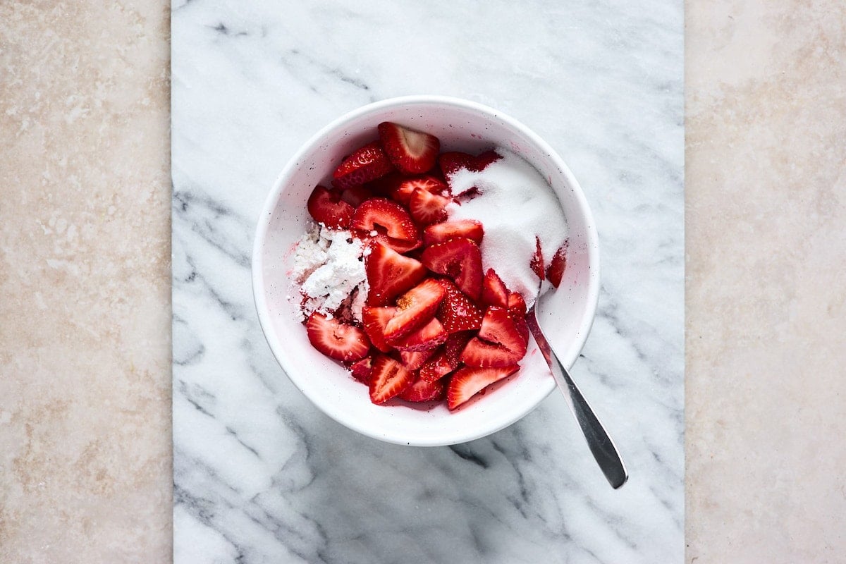 sliced strawberries in bowl with sugar and cornstarch. 