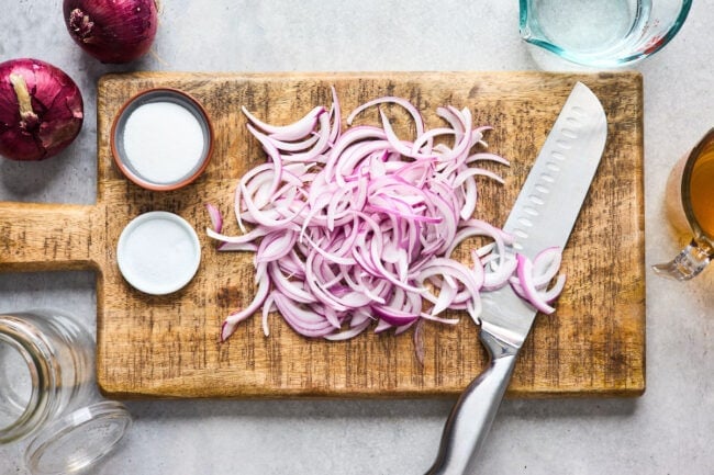 slices of red onion on a cutting board with knife