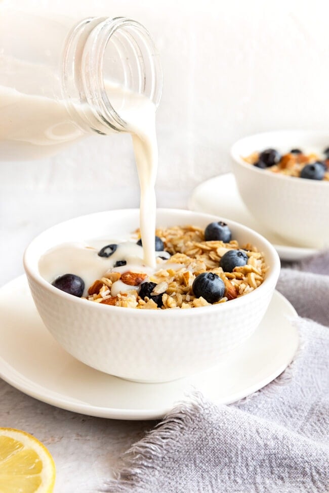 milk being poured into a bowl of lemon blueberry granola.