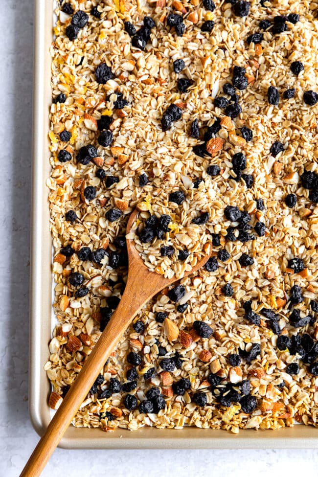 lemon blueberry granola on pan with wooden spoon.