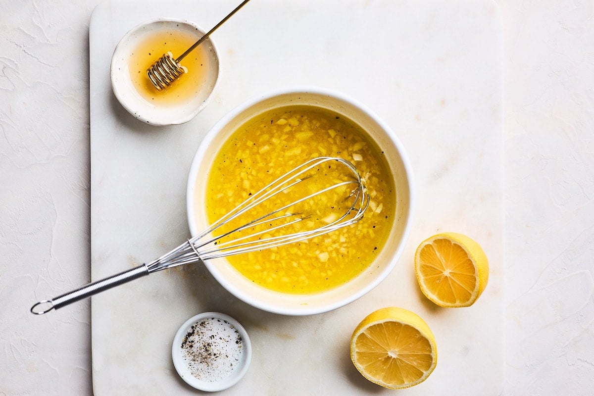 lemon dressing in bowl with whisk for chicken pasta salad. 