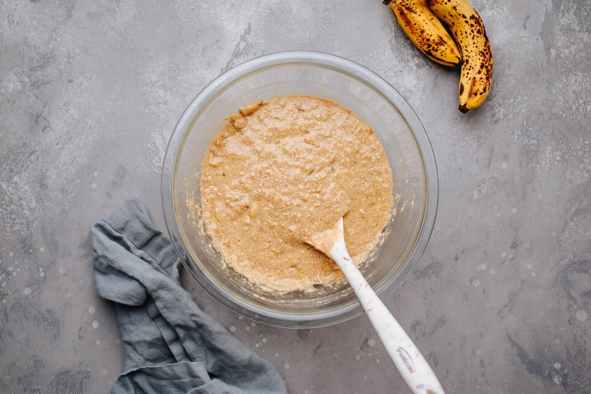 healthy banana muffin batter in bowl with spatula. 