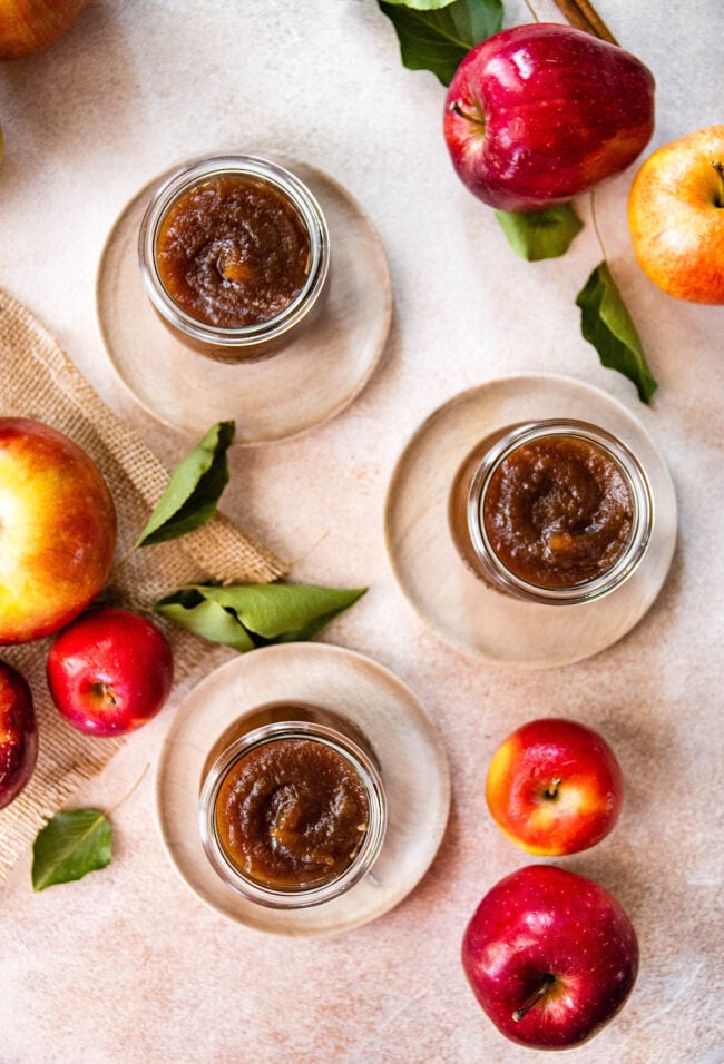 Apple Butter in jars on plates with apples. 
