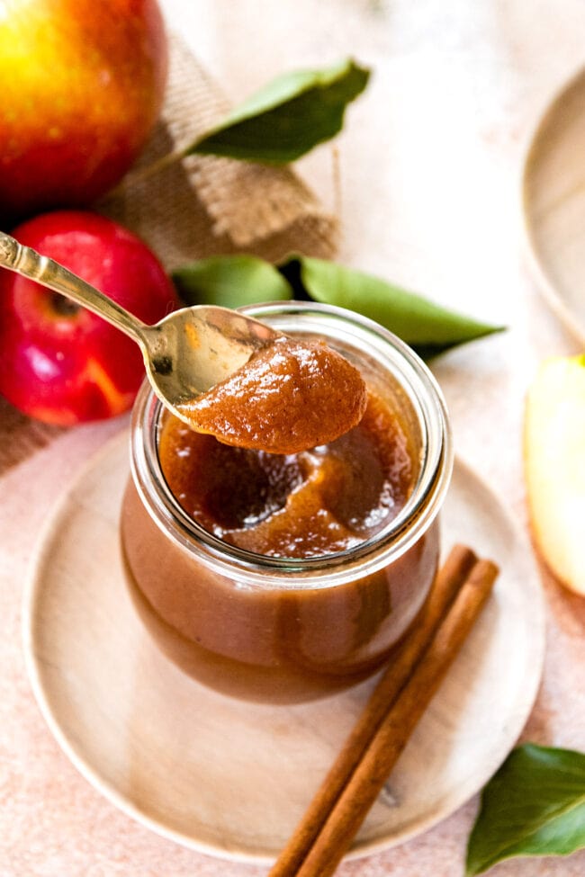 jar of apple butter with some on a spoon.