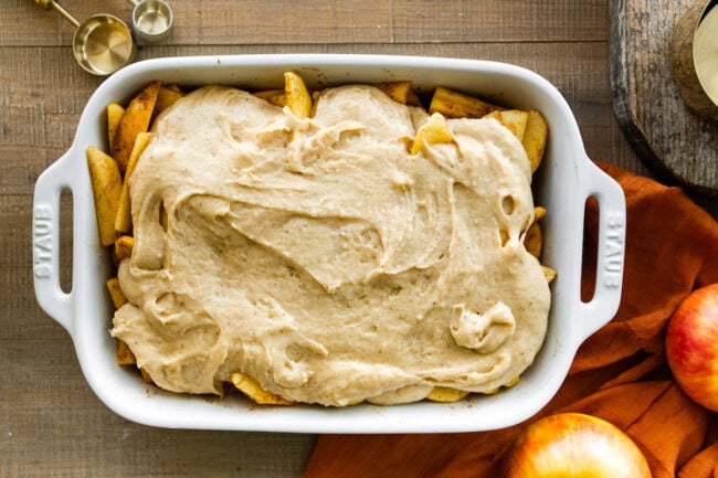 sliced apples in baking dish with apple cobbler topping.