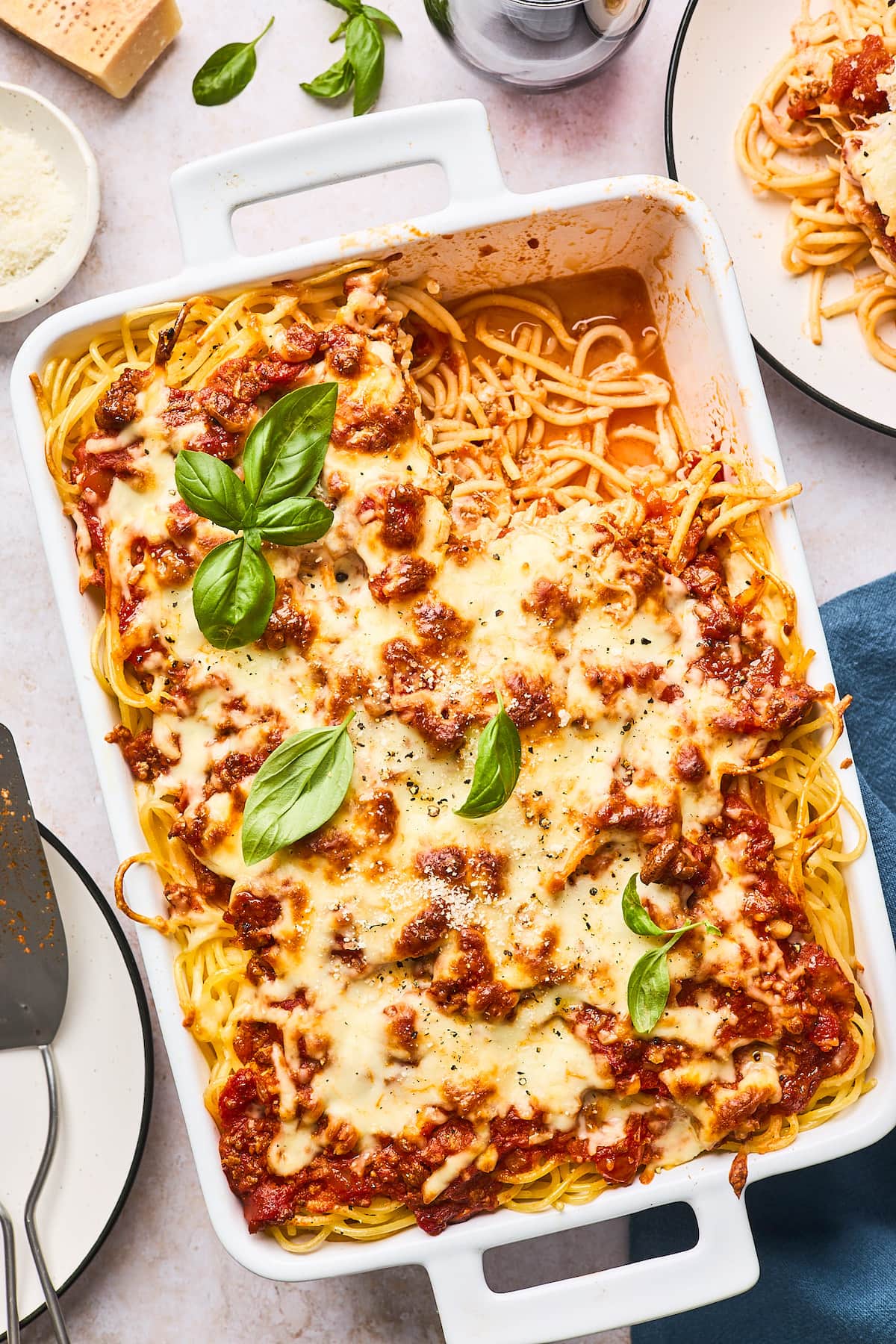 Baked spaghetti in white baking dish with melted cheese. 