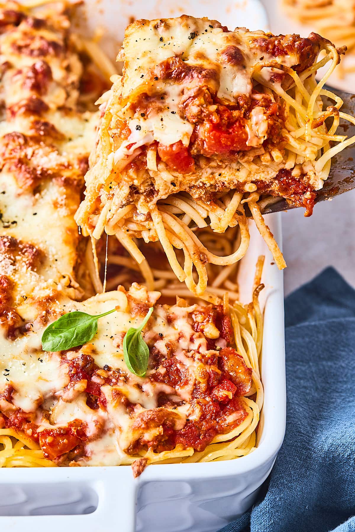 Baked spaghetti being lifted out of the pan with spatula. 