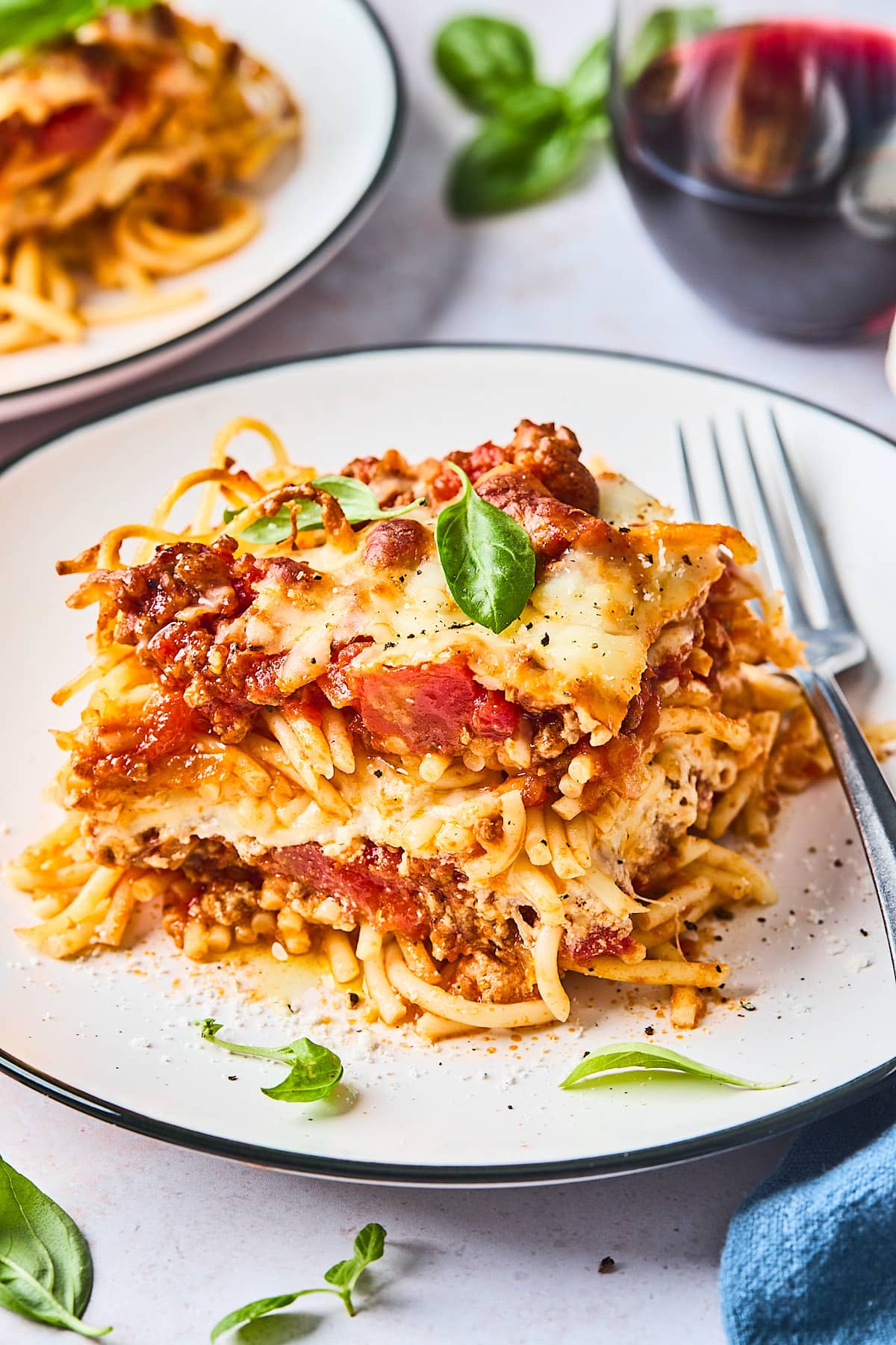 baked spaghetti on plate with basil and fork. 