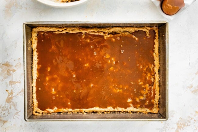 Biscoff caramel cookie bars in pan with layer of caramel sauce