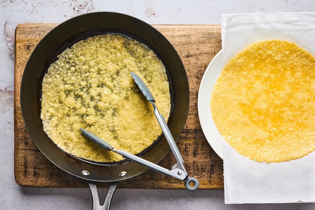 tortilla in oil in pan with tongs. 