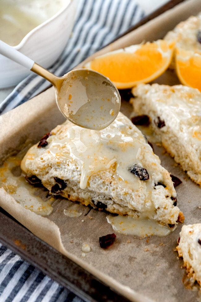 cranberry orange scones on pan with glaze. 