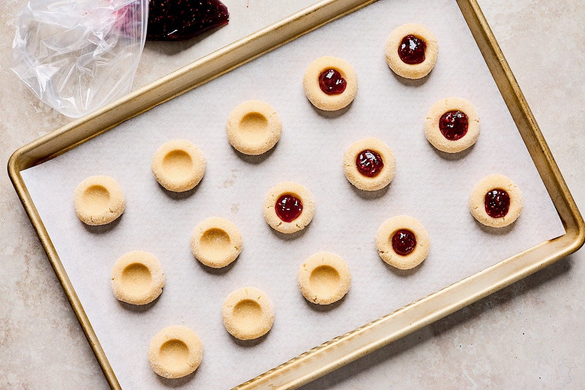 thumbprint cookies on cookie sheet with parchment paper. 