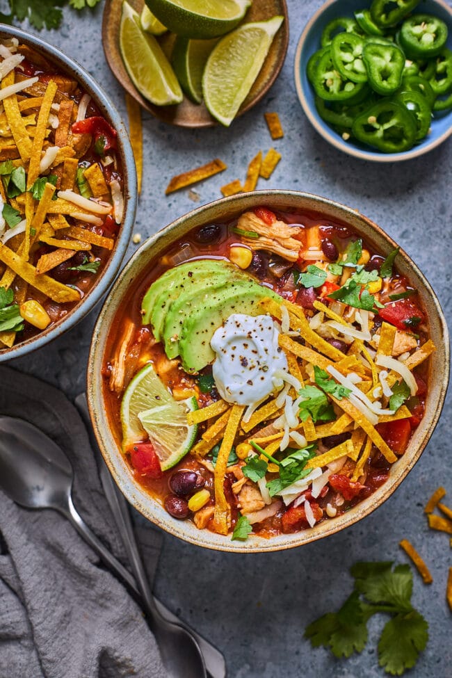 chicken tortilla soup with tortilla strips and toppings in bowl.