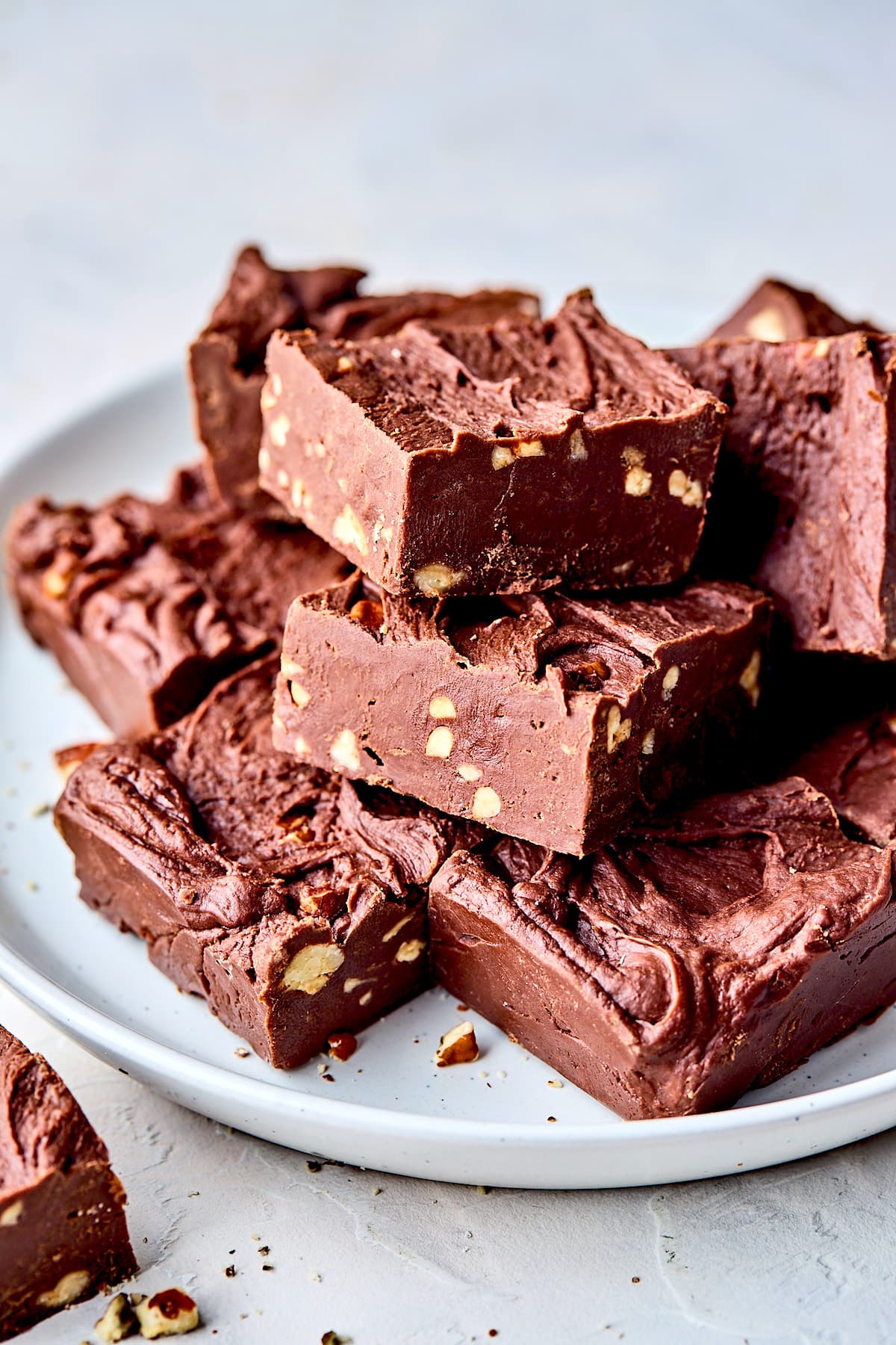 chocolate fudge with walnuts cut into squares on plate. 