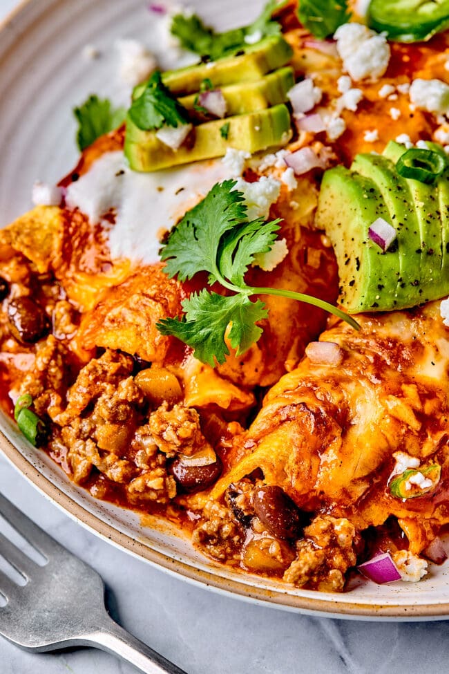 cheesy beef enchiladas on plate with toppings