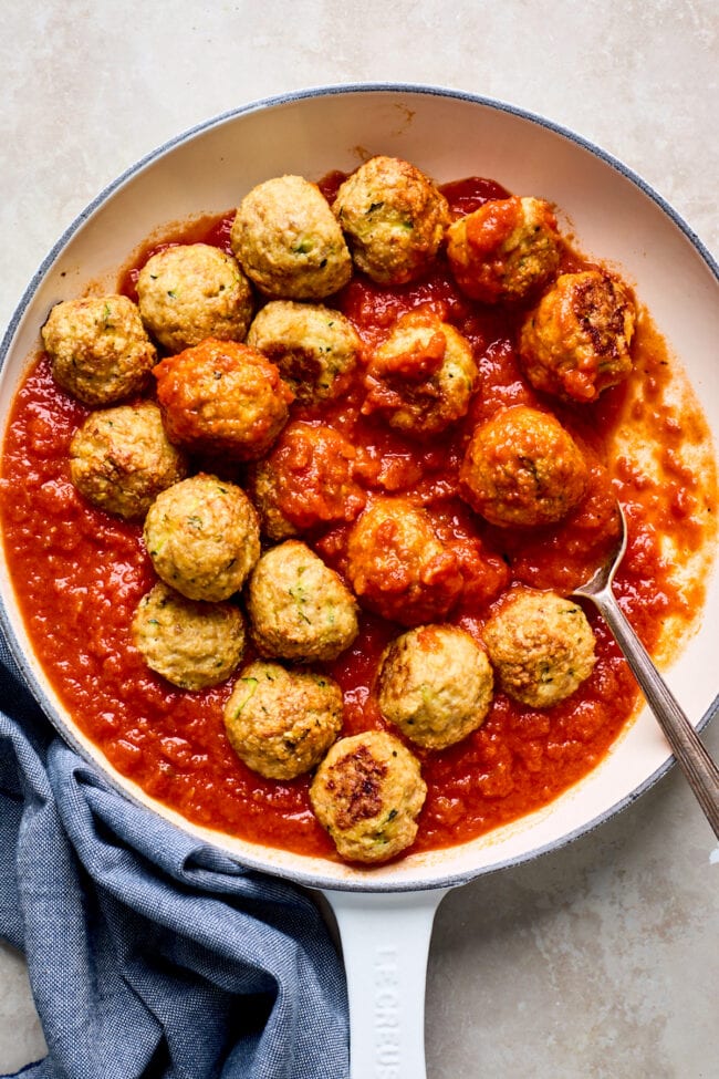 chicken meatballs in pan with marinara sauce and spoon