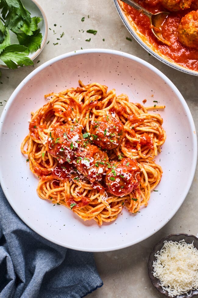 chicken meatballs with spaghetti in a bowl with marinara sauce and Parmesan cheese