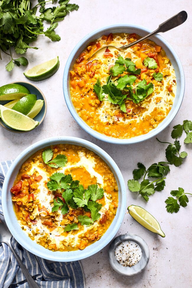 curry lentil soup in 2 bowls with cilantro and coconut milk