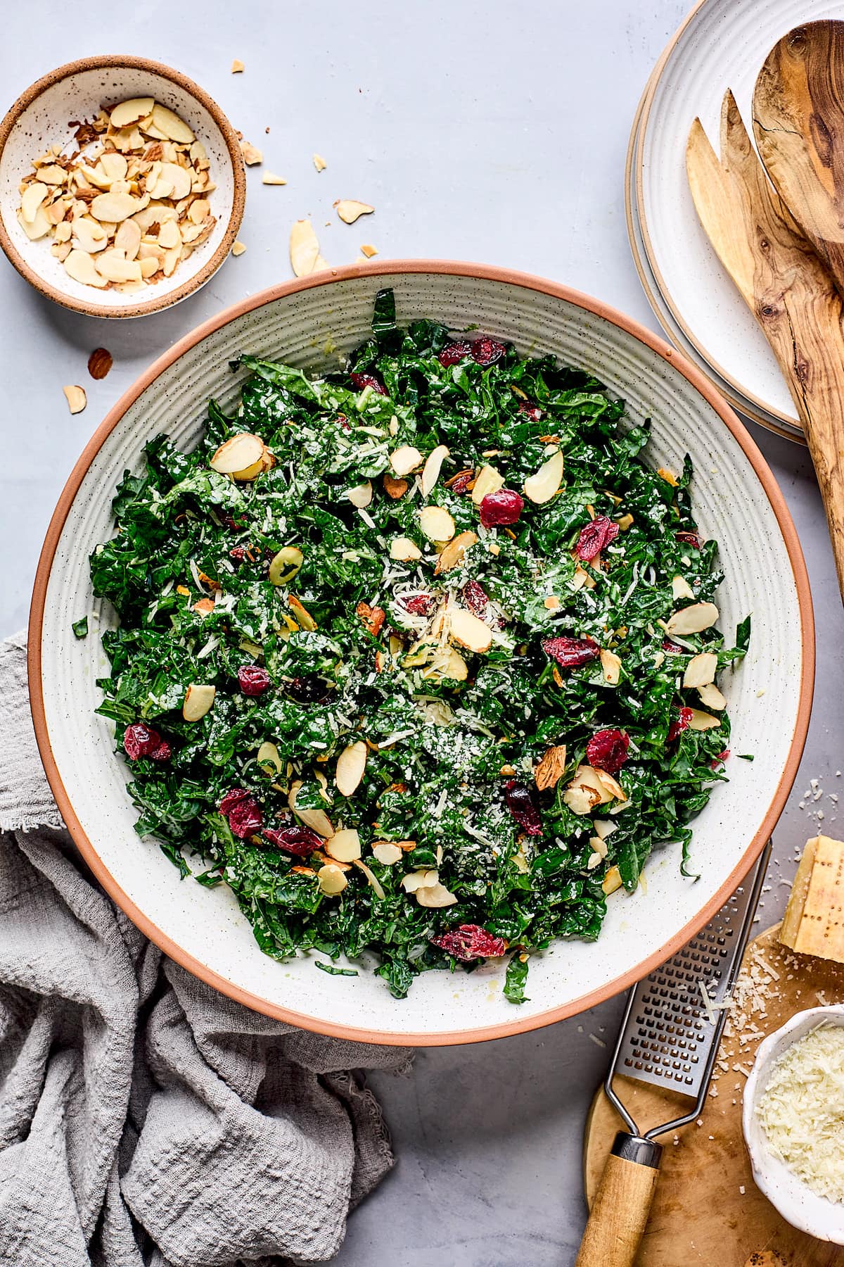 kale salad with dried cranberries, almonds, and Parmesan cheese in large bowl. 