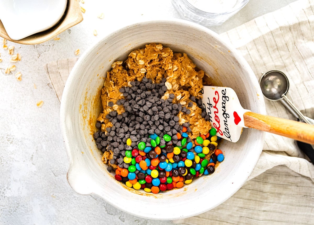 monster cookie energy ball ingredients in bowl with spatula.
