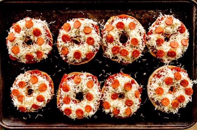 pizza bagels with mozzarella cheese and pepperoni on baking sheet