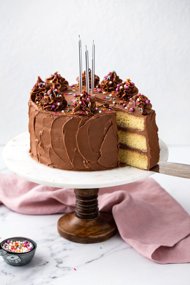 yellow cake with chocolate frosting on a cake stand