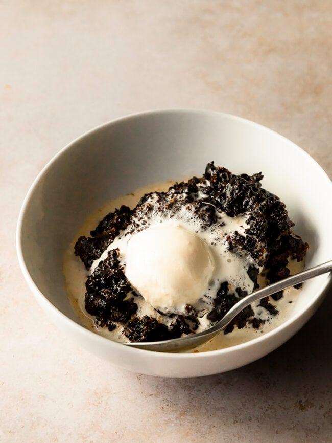 chocolate pudding cake in bowl with vanilla ice cream and spoon