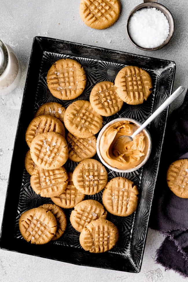 3 ingredient peanut butter cookies on baking sheet with bowl of peanut butter