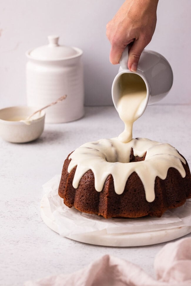 banana bundt cake with cream cheese icing being poured over the top