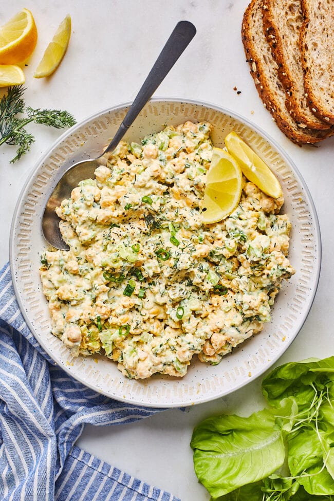 chickpea salad in bowl with lemon wedges and spoon