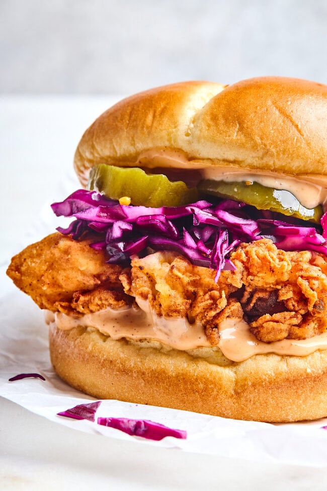 fried chicken sandwich with sauce, cabbage slaw, and pickles