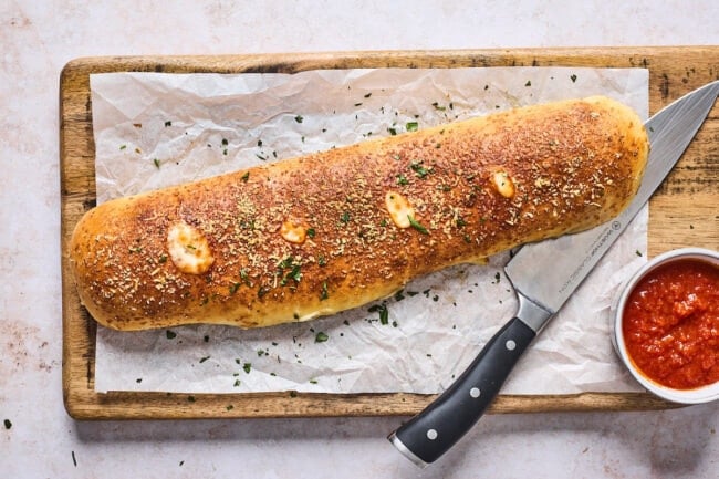 baked Stromboli on cutting board with knife