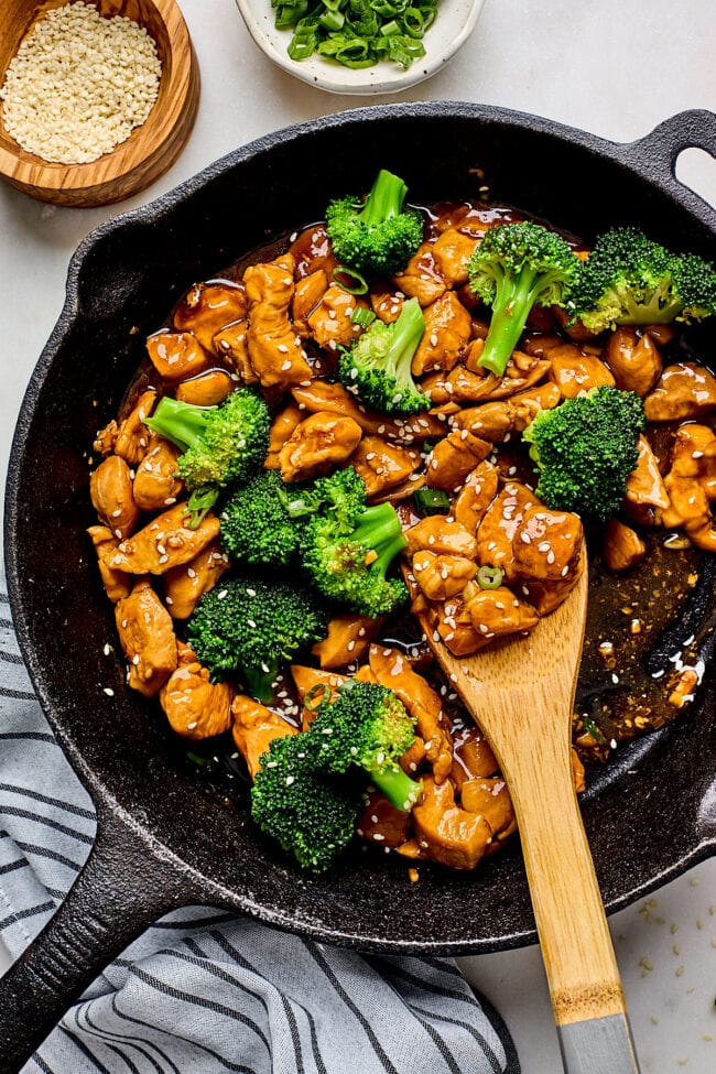 chicken teriyaki in skillet with broccoli and wooden spoon