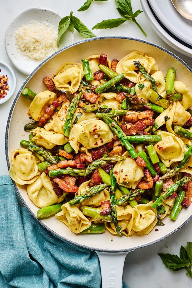cheese tortellini with bacon, asparagus, and brown butter in skillet
