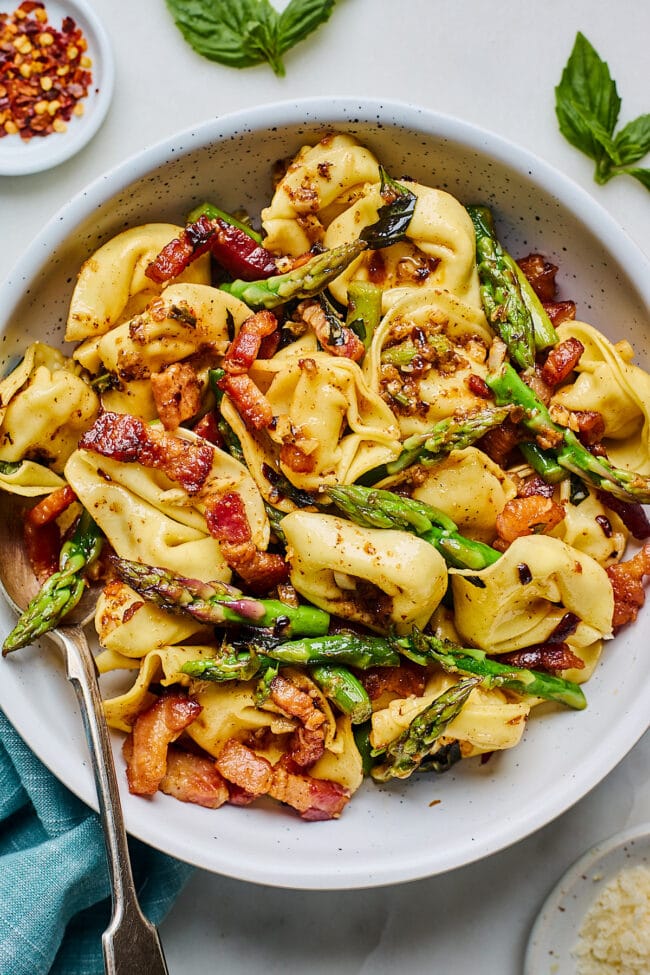 brown butter bacon tortellini with asparagus in bowl with spoon