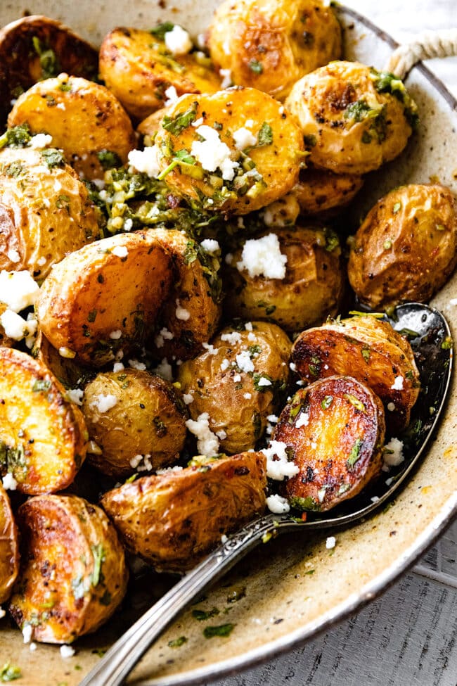 chimichurri roasted potatoes with queso fresco in bowl with spoon.
