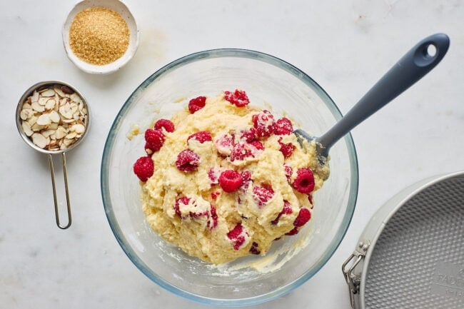 raspberry almond ricotta cake batter in a bowl with spatula