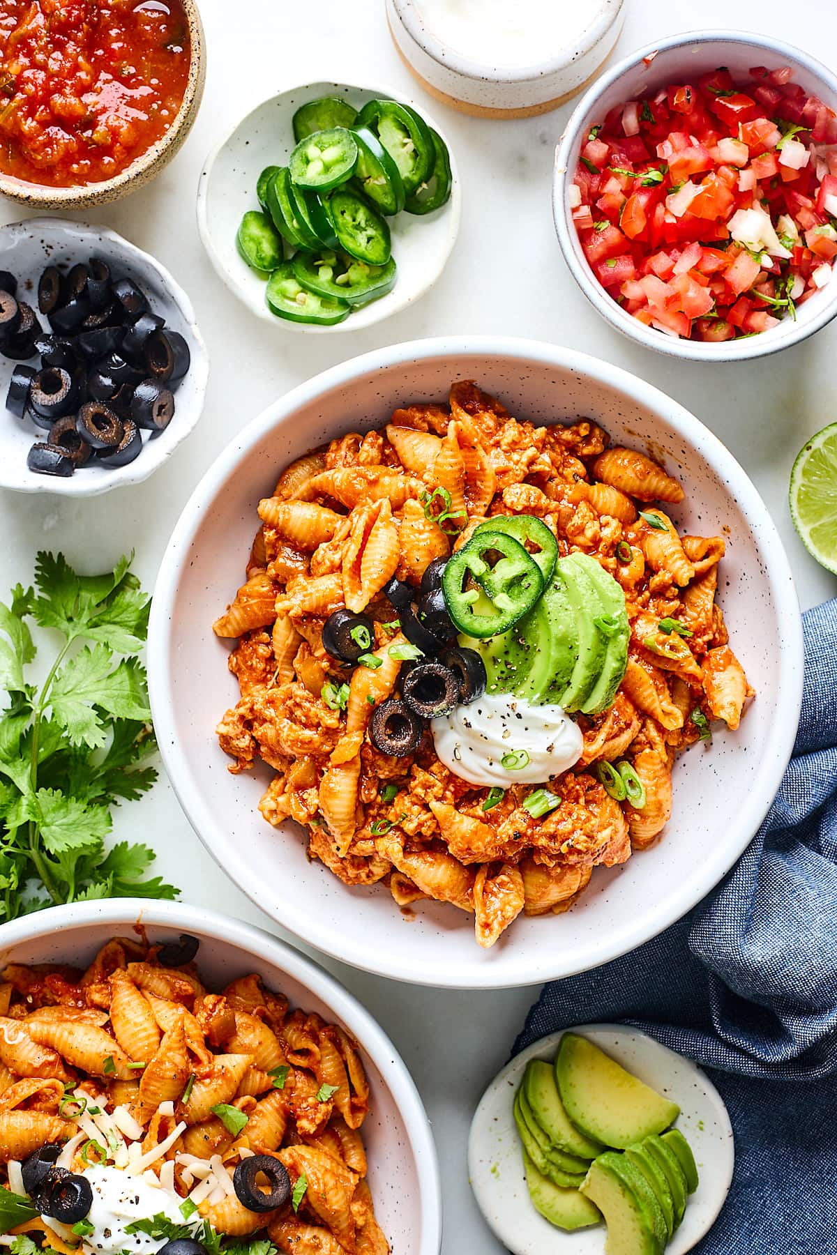 taco pasta in bowl with black olives, avocado, sour cream, and jalapeño slices. 