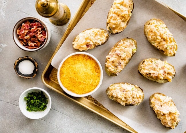 twice baked potatoes stuffed with filling on baking sheet