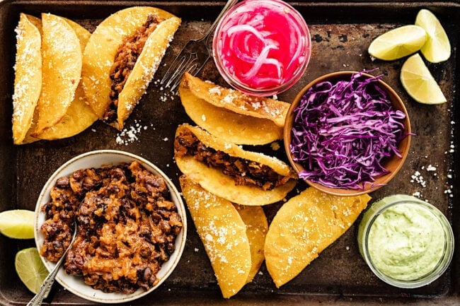 black bean tacos in crispy taco shells with pickled red onions, cabbage, and avocado sauce