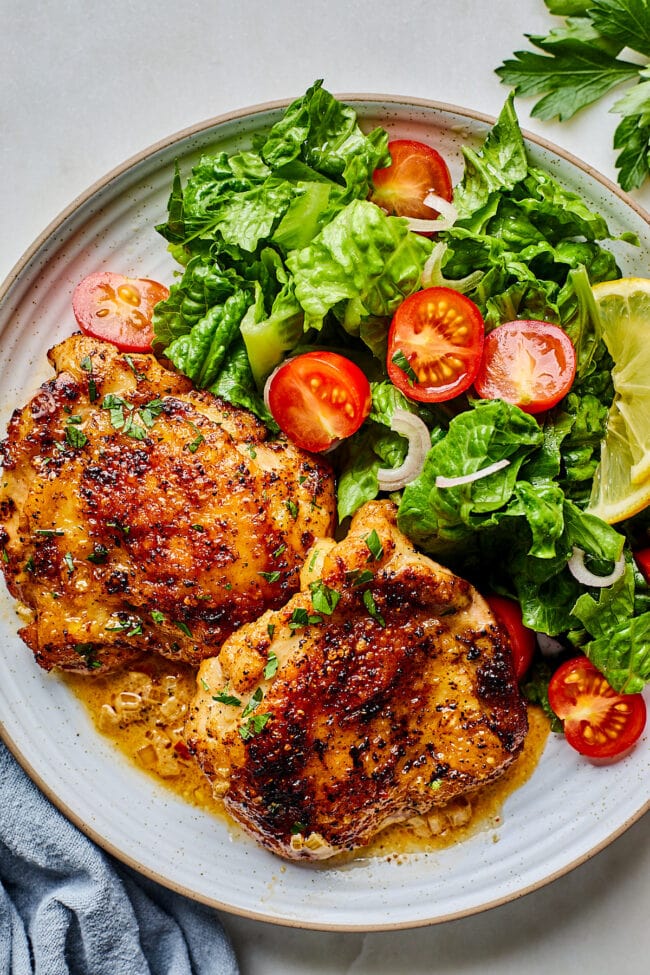 chicken thighs on plate with salad.