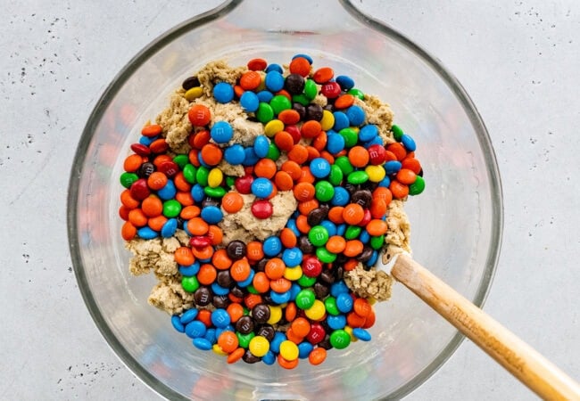 M&M cookie dough in bowl with spatula.