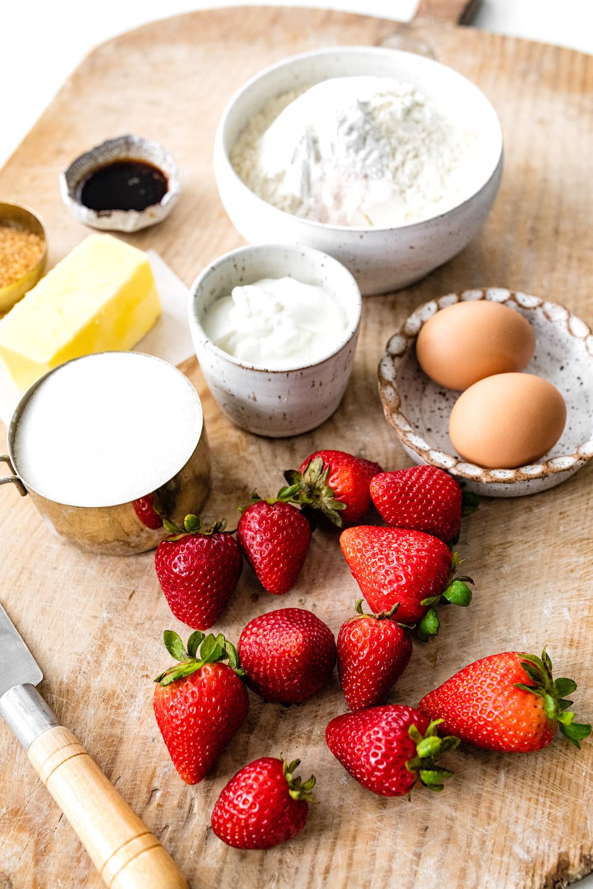 strawberry muffin ingredients in bowls and fresh strawberries on wood board. 