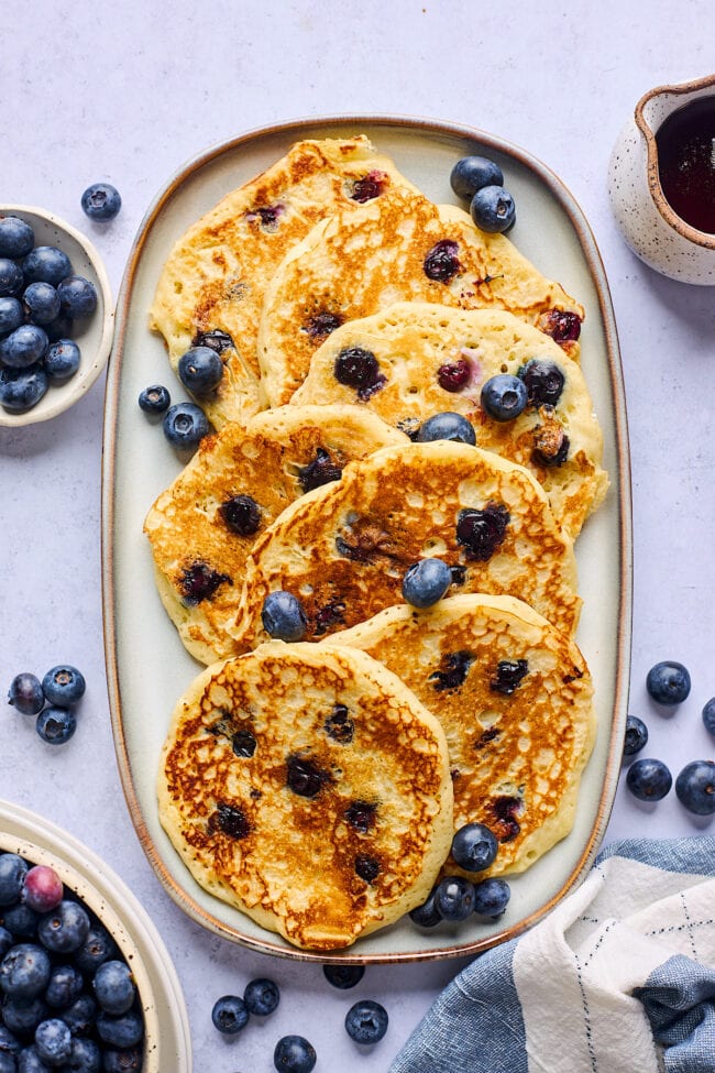 blueberry pancakes on platter with fresh blueberries.