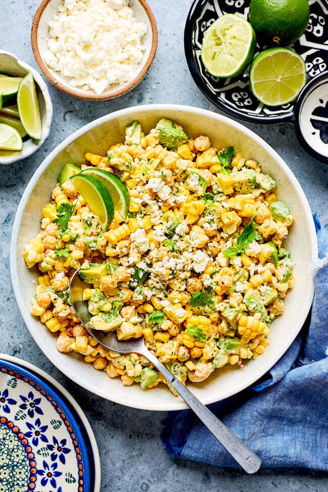 chipotle chickpea corn salad in bowl with spoon and limes. 