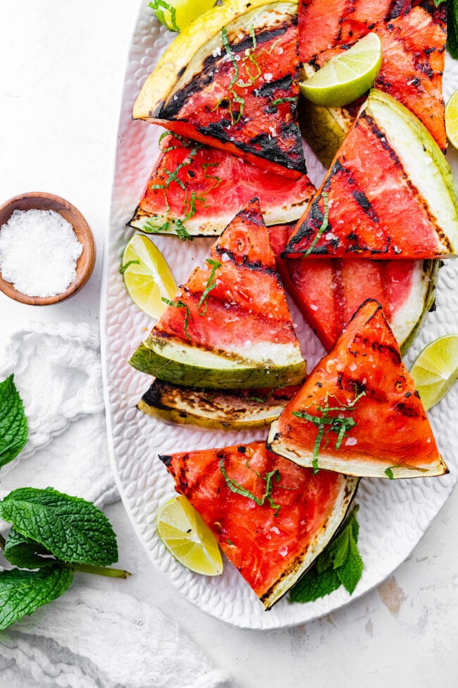 grilled watermelon on platter with lime and mint. 