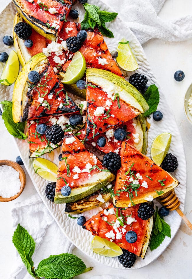 grilled watermelon wedges on platter with mint and berries. 